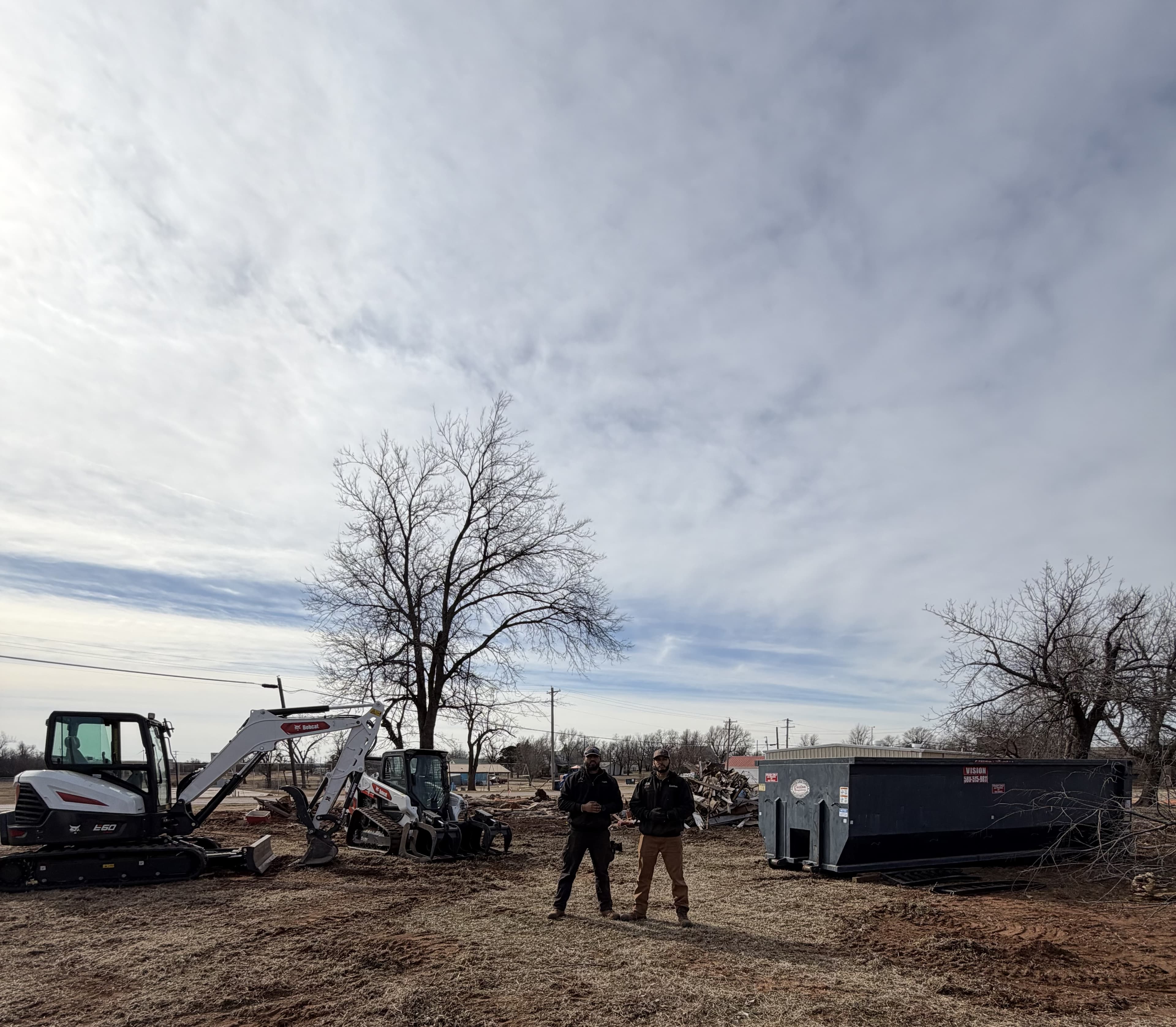 Big Project Solutions crew with a Bobcat E60, skid steer and roll-off on a cleared lot outside Oklahoma City